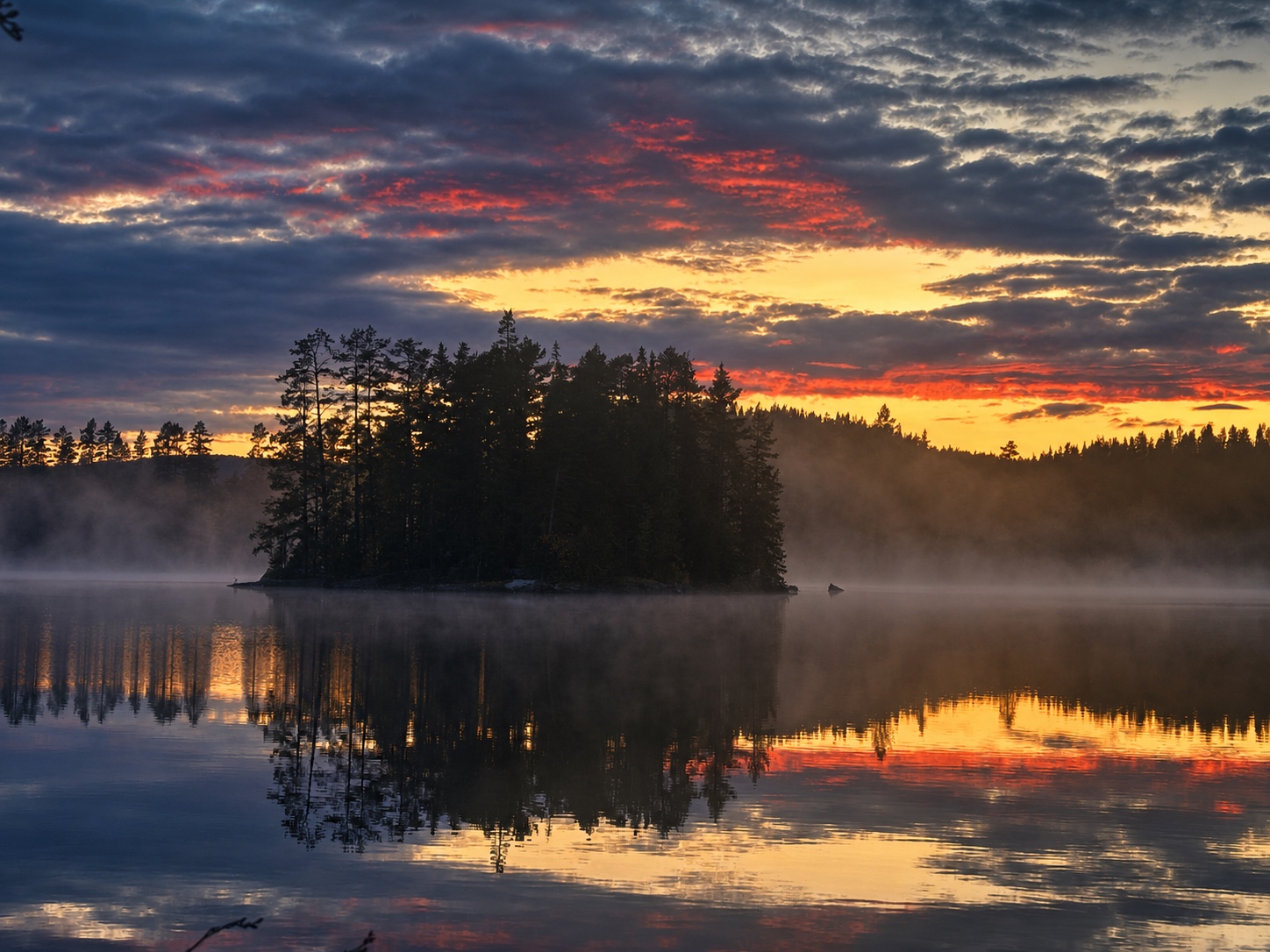 Ein ruhiger See mit bewaldeter Insel im goldroten Abendlicht
